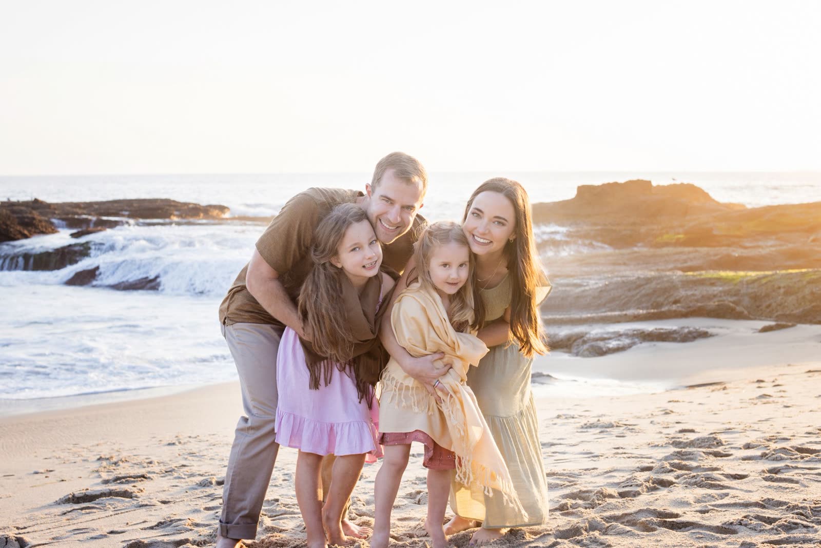 A family of four together on the sand at Montage, Laguna Beach, in golden evening light